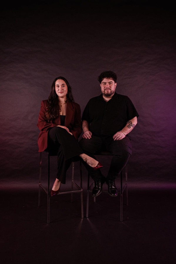 Ema en Andrés ten voeten uit op barkrukken, paarse achtergrond